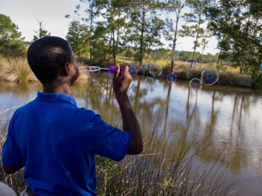 Windwood resident boy blows bubbles toward pond